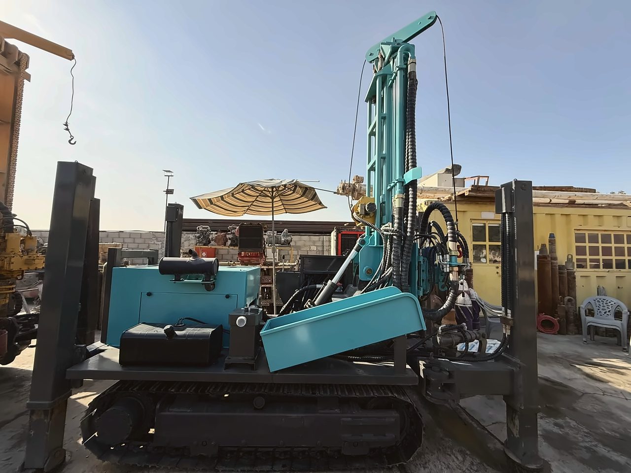 Teal crawler-mounted drilling rig with its mast upright