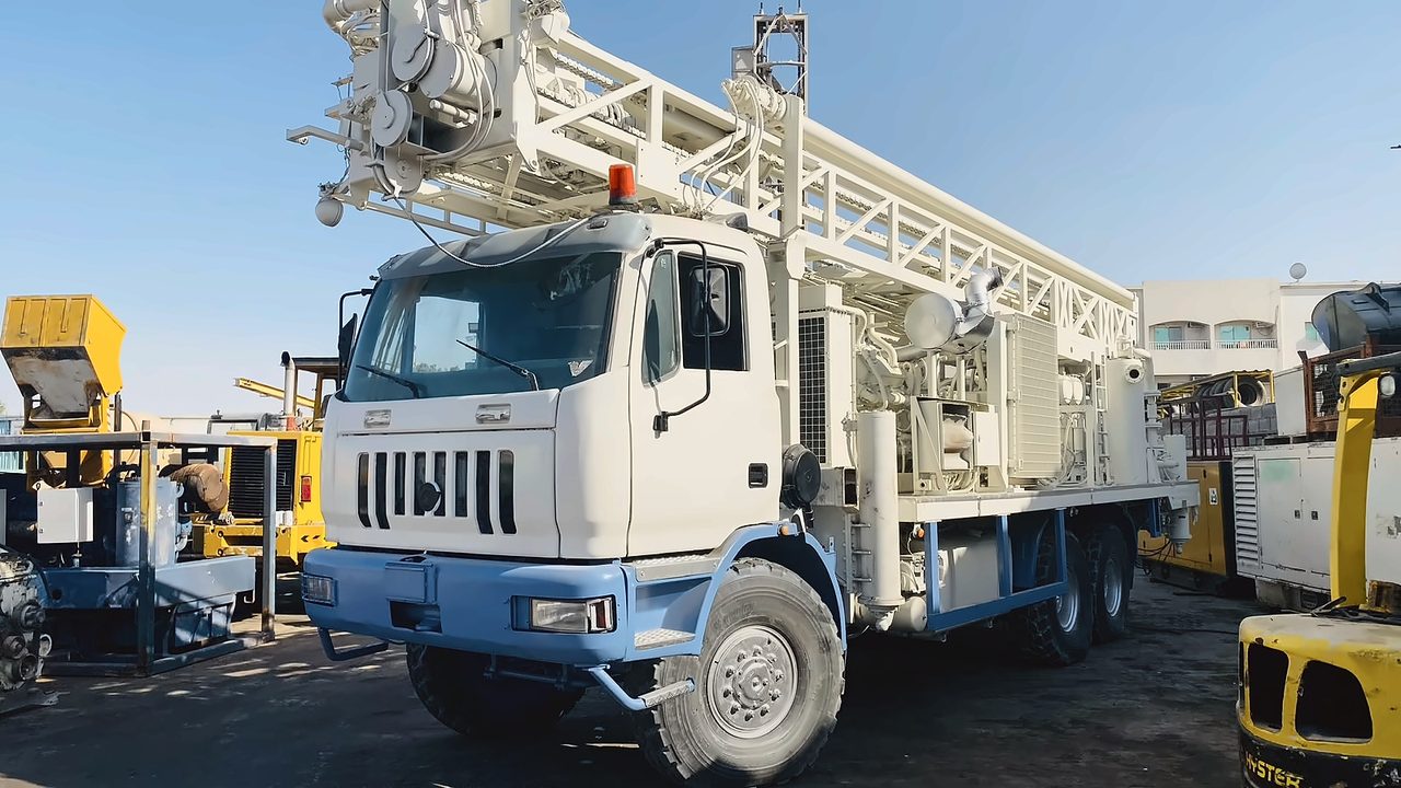 Truck-mounted drilling rig on a white truck, front three-quarter view